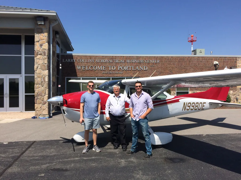 3 Men with a Small Propeller Aircraft Outside the Aeronautical Business Center